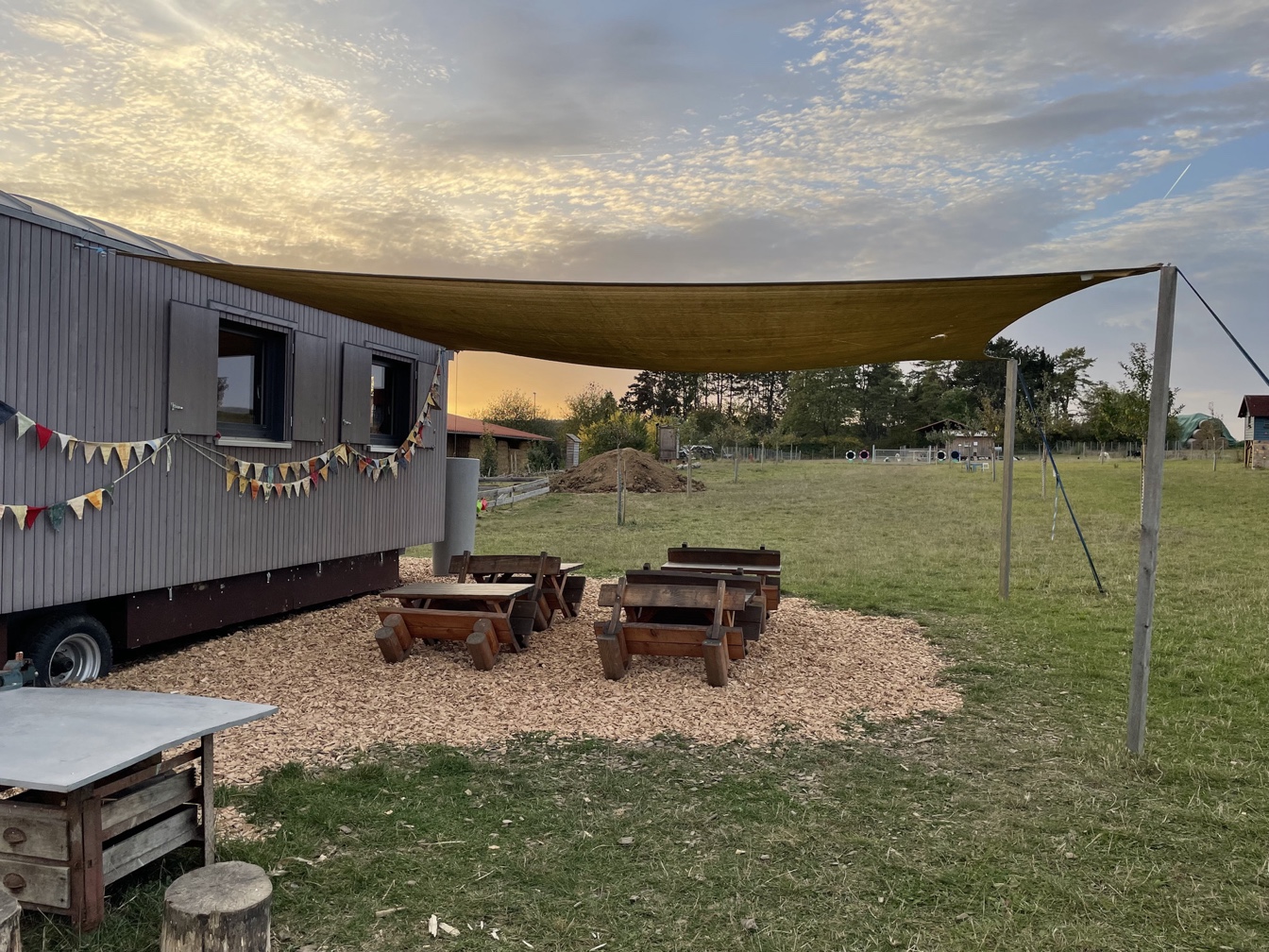 Bauwagen mit Sonnensegel im Abendlicht